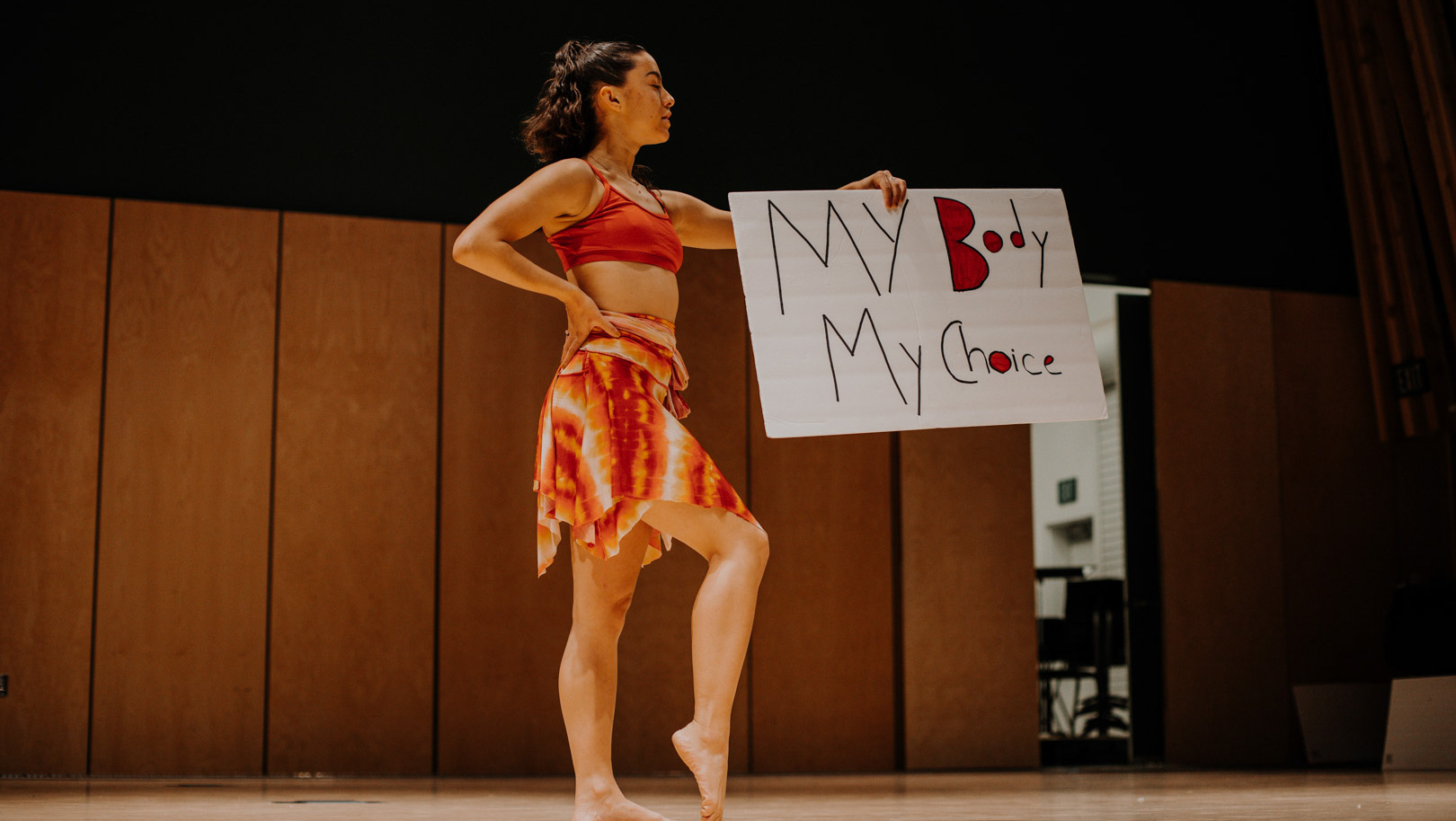 An art in society student performing and holding a sign that reads, "My body my choice".