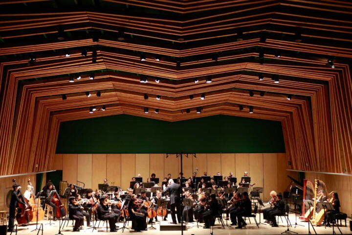 An orchestra performing in a concert hall.