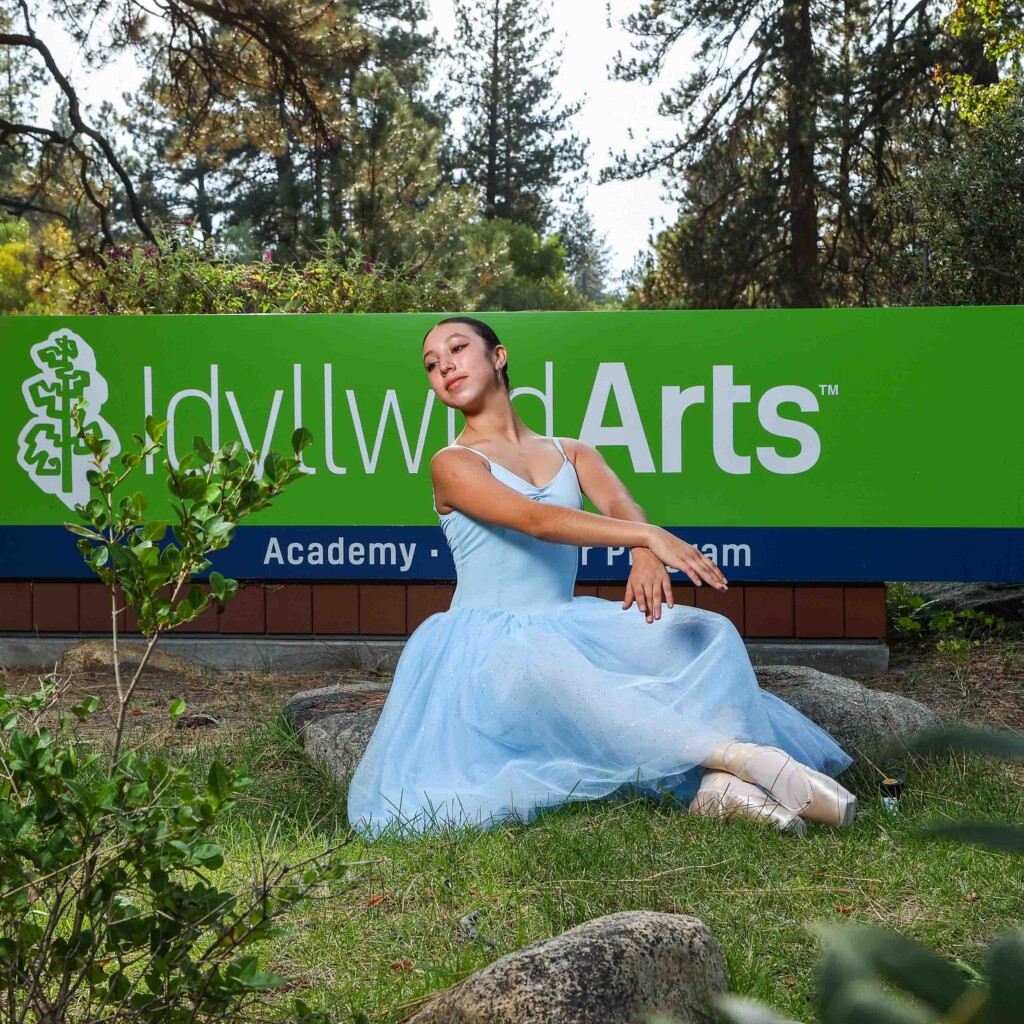 A dancer poses in front of the Idyllwild Arts sign.