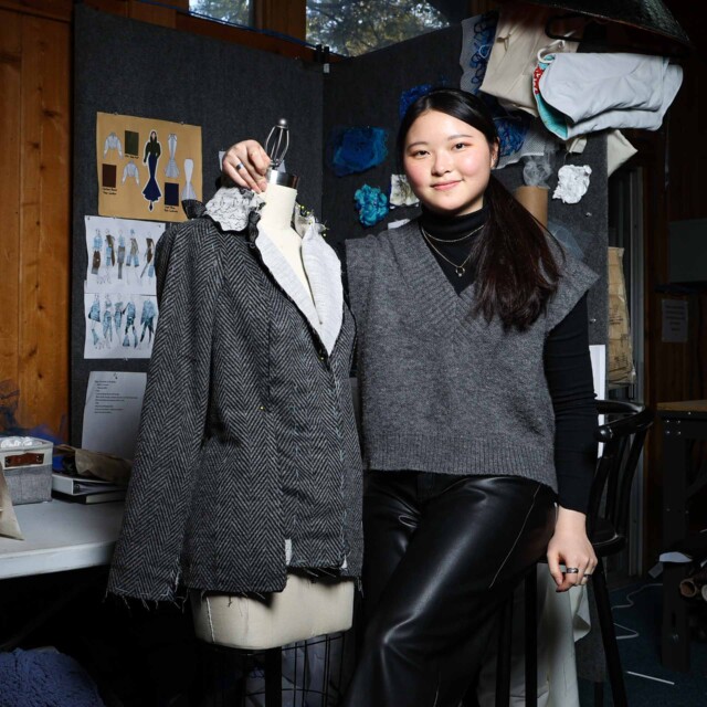 A fashion design student alongside her work.