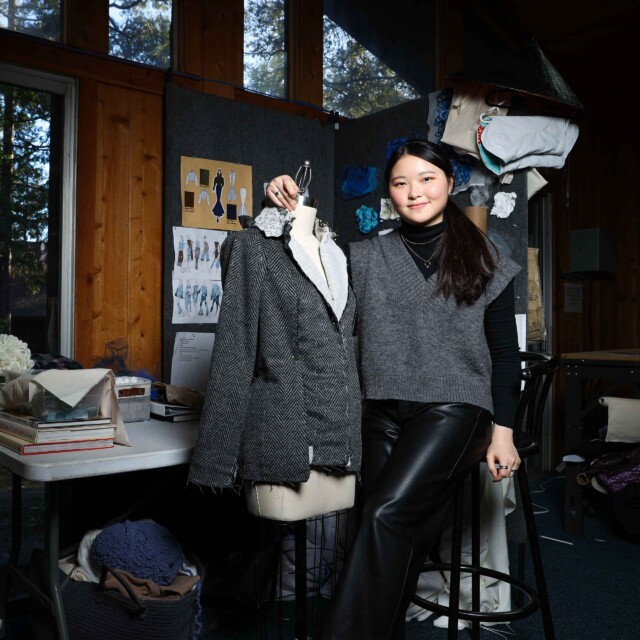 A fashion design student alongside her work.