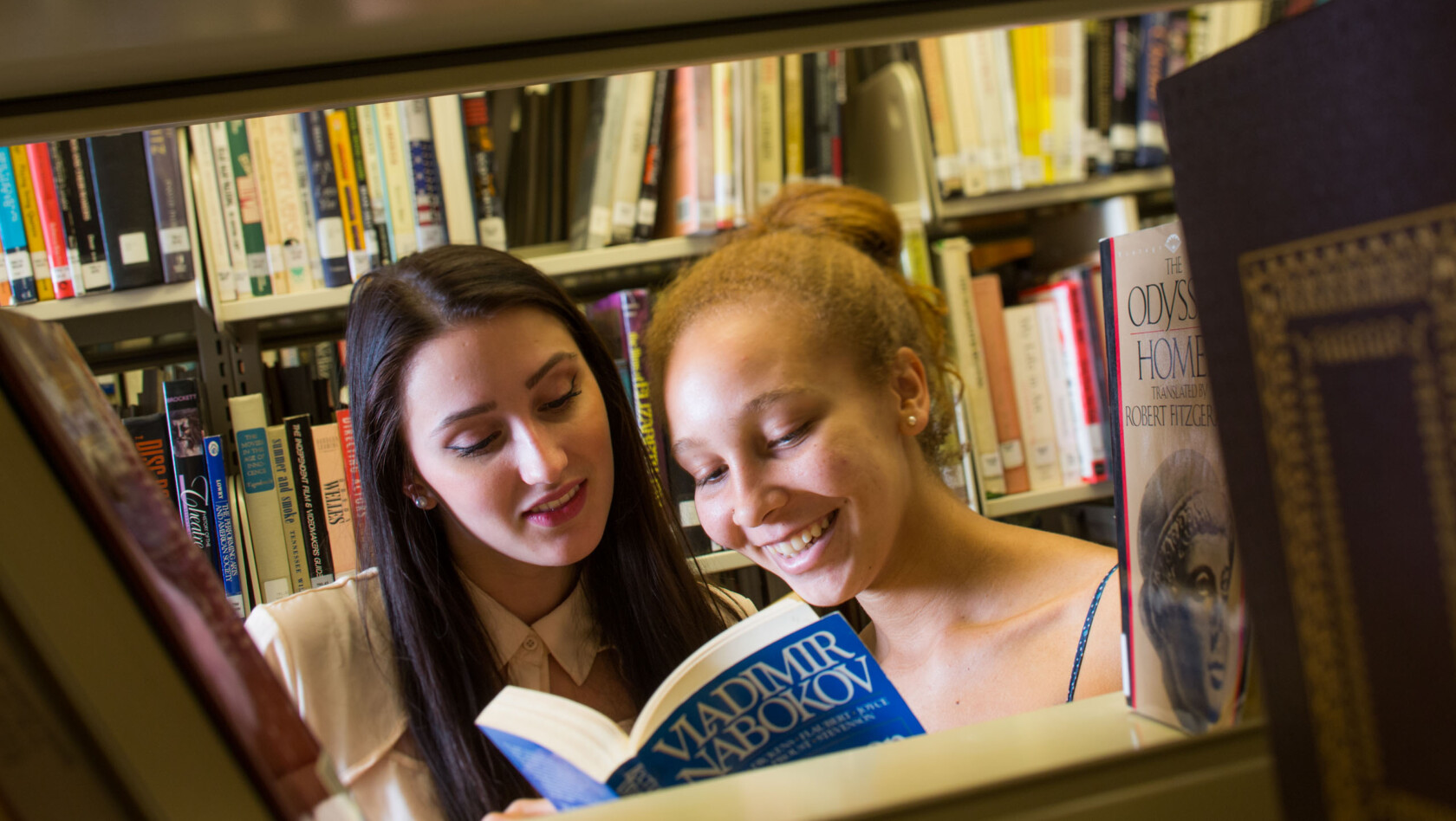 Two Humanities students reading a book in a library.